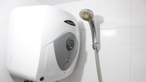A wall-mounted shower unit with a control panel and a handheld showerhead. - Relaxing 2BR Apartment at Buah Batu Park (Dayeuhkolot)