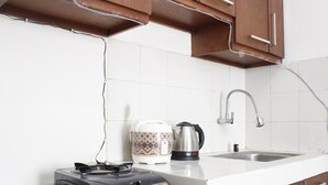 A kitchen with a gas stove, a kettle, and a coffee maker on the counter. - Relaxing 2BR Apartment at Buah Batu Park (Dayeuhkolot)