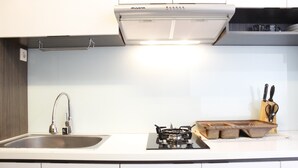 Uma cozinha moderna com uma pia de aço inoxidável, fogão a gás e exaustor.