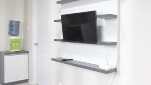 A modern living room with a flat-screen TV mounted on a wall, a water dispenser, and a cabinet.