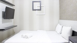 A hotel room with a bed, a flat-screen TV mounted on a wall, and a decorative wall panel.