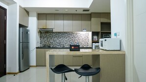 Une cuisine moderne dotée d’un îlot central intégré, d’un réfrigérateur en acier inoxydable, d’un four à micro-ondes et d’un dosseret carrelé.