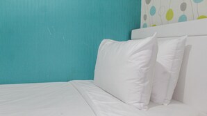 A bed with white bedding and pillows, a teal wall, and a colorful abstract wall art piece above the bed. - Modern and Relax 2BR @ Bassura City Apartment (Jakarta)