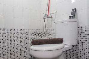 A bathroom with a toilet, a shower, and a tiled wall. - Best View 2BR Apartment at Bassura City (Jakarta)