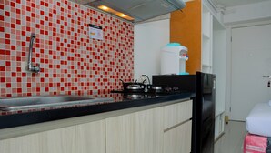 A kitchen with a tiled backsplash, a sink, a stove, and a refrigerator.