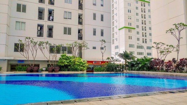 A swimming pool surrounded by a multi-story residential building with balconies and a visible shop sign.
