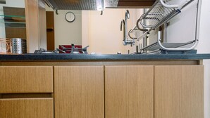 A kitchen with wooden cabinets, a stainless steel sink, and a metal drying rack.
