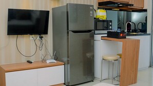 Een moderne keuken met een roestvrijstalen koelkast, een inbouwoven, een magnetron en een klein barretje.