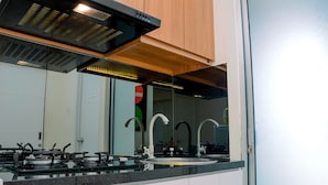 Een moderne keuken met een gasfornuis, een spoelbak en een houten kastje boven het aanrecht.