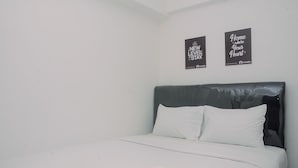 A neatly made bed with white linens and pillows, a dark headboard, and two motivational posters on the wall. - 1BR Fully Furnished Bassura City Apartment (Jakarta)