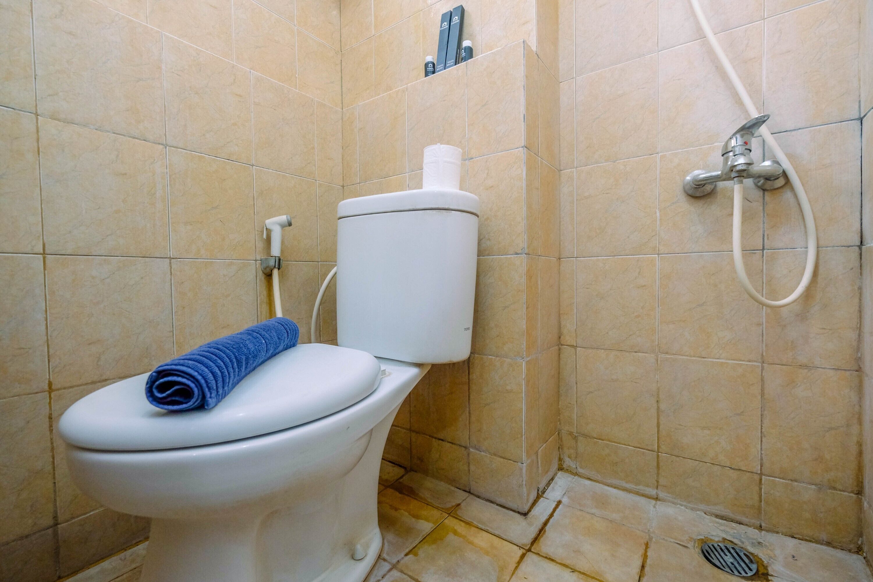 Une salle de bain avec des toilettes, une douche et un mur carrelé.
