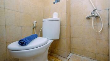 Une salle de bain avec des toilettes, une douche et un mur carrelé.