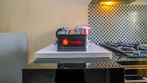 Una encimera de cocina con una bandeja que contiene agua embotellada y una térmica, un bolso de viaje con la etiqueta 'Travelio', y un salpicadero de azulejos.