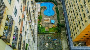 Vista aérea de un edificio residencial con piscina, balcones y un pequeño jardín.