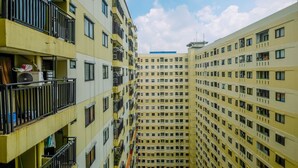 Un edificio residencial de varios pisos con balcones, unidades de aire acondicionado y un cielo despejado.