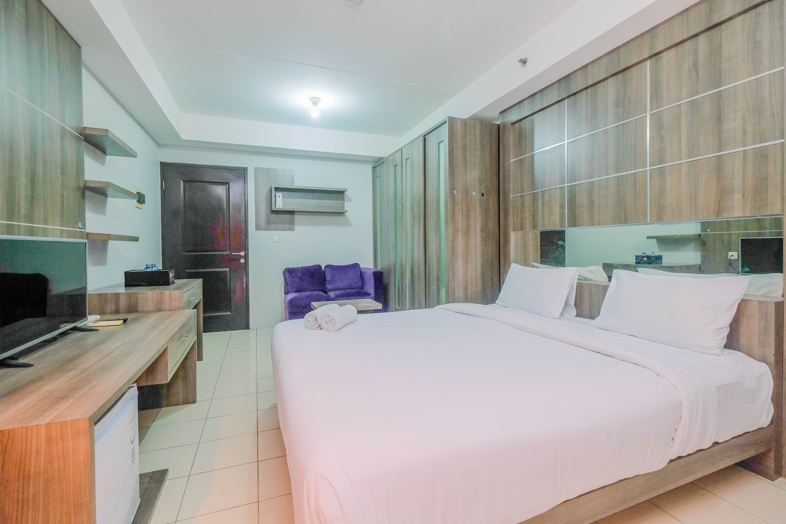 A hotel room with a bed, a desk, a chair, and a wardrobe.