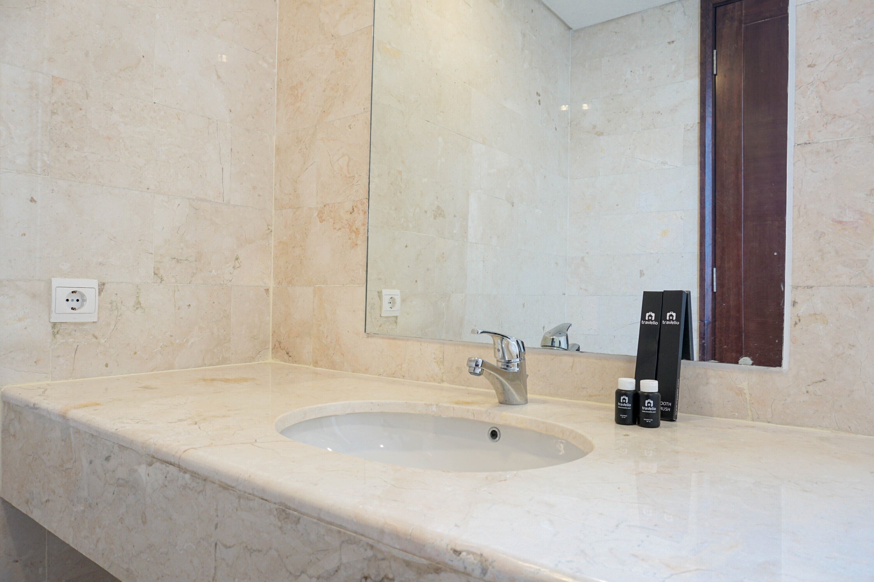 A bathroom with a marble sink, a mirror, and a door.