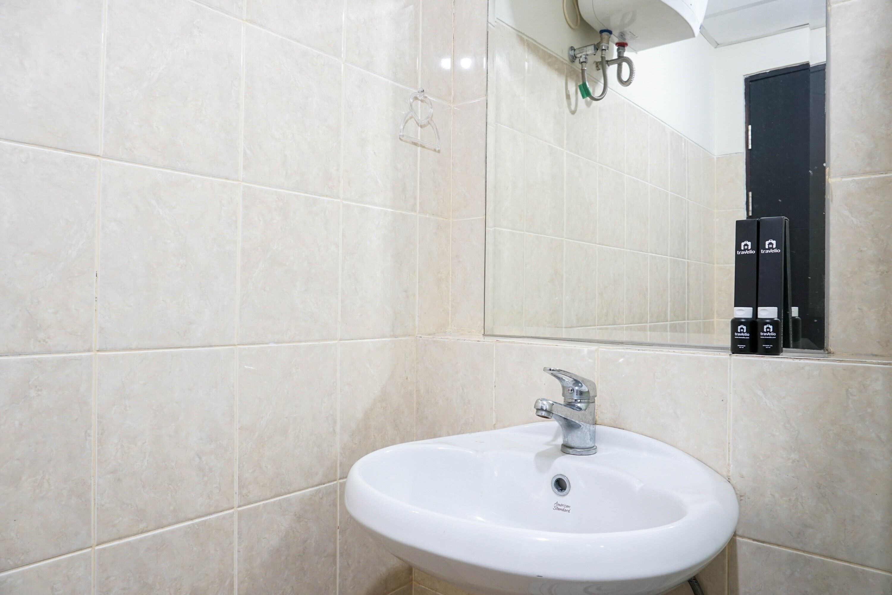 A bathroom with a white sink, a mirror, and beige tiles.