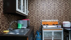 A compact kitchen with a sink, a gas stove, and a small cabinet. - Amazing 1BR Apartment at The Wave @ Rasuna Epicentrum (Jakarta)