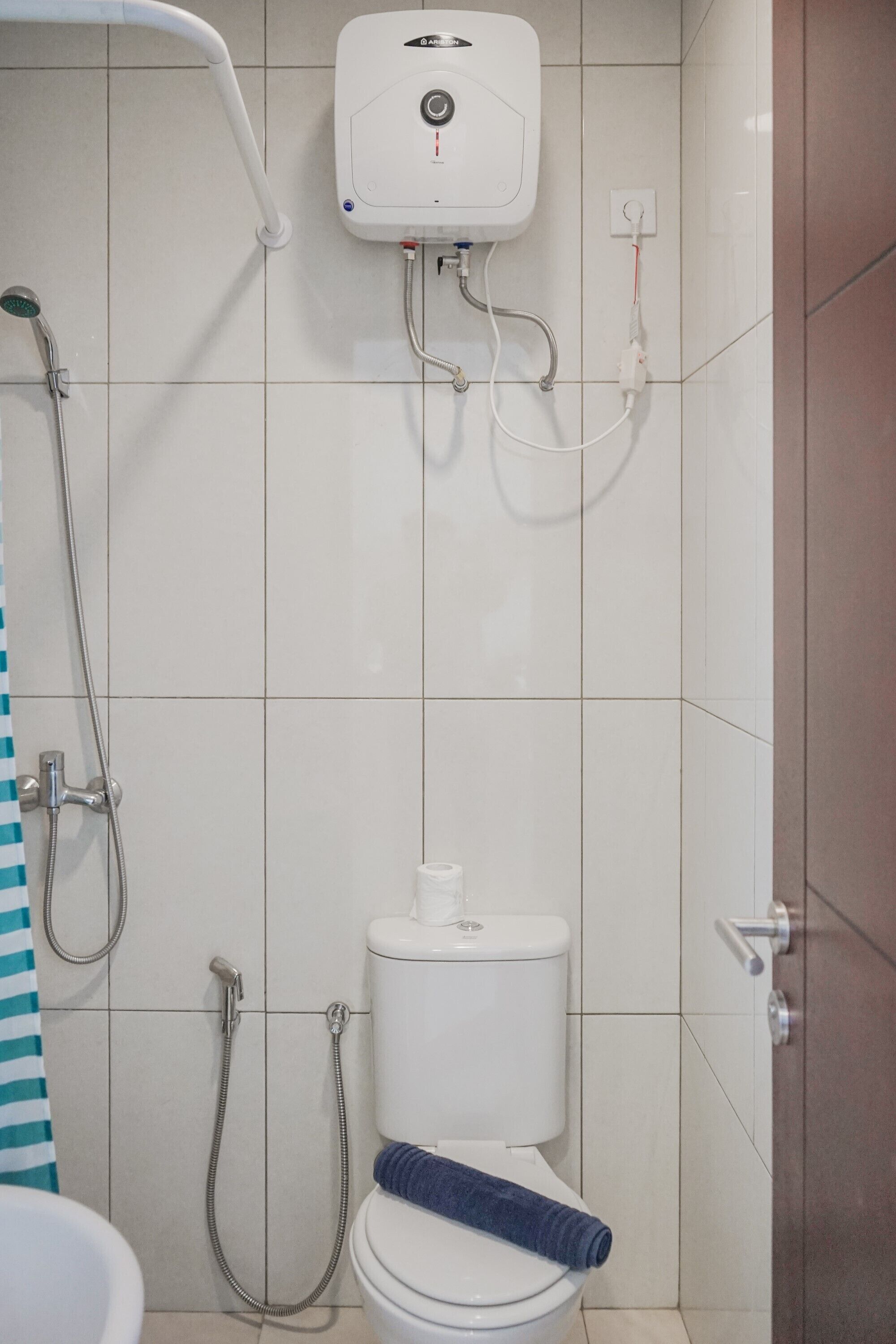A bathroom with a toilet, a shower, and a towel rack.