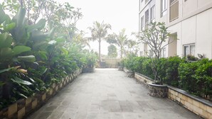 A paved courtyard with potted plants and a building in the background. - Minimalist & Comfy 2BR @ Titanium Square Apartment (Jakarta)
