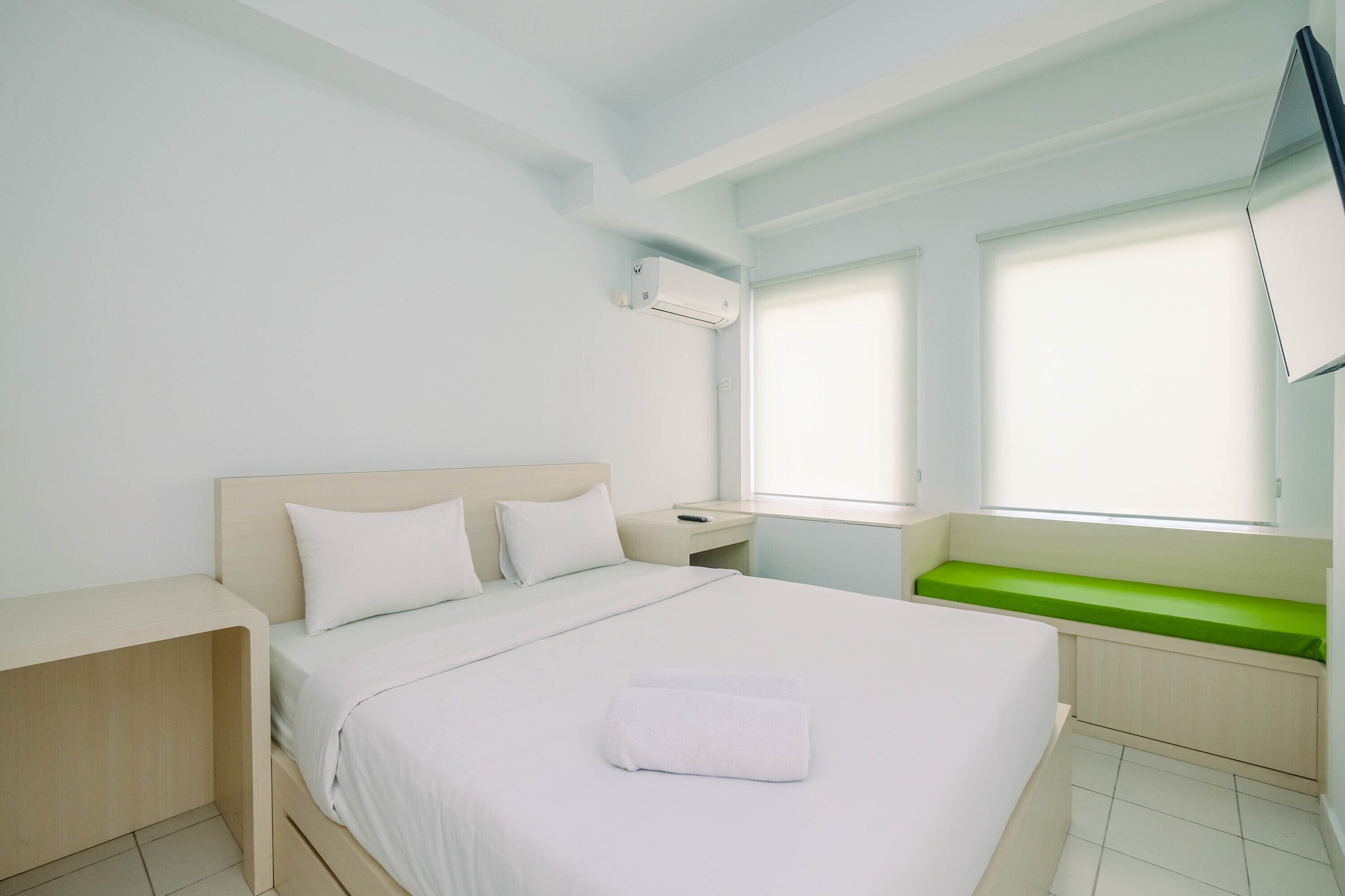 Ein Hotelzimmer mit Bett, Nachttisch und einem Fenster mit Jalousien.