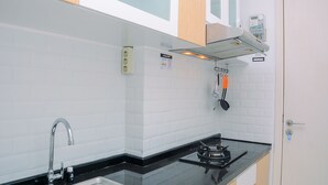 Una cucina con piano di lavoro nero, zoccolo di piastrelle bianche e pensili in legno.