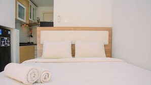 Camera d'albergo con un letto, una testata in legno e una zona cucina sullo sfondo.