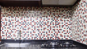 Cozinha com painel atrás do fogão revestido em azulejos com padrão vermelho, branco e azul.