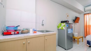 Een kleine keuken met een koelkast, een spoelbak en een aanrecht met diverse spullen.