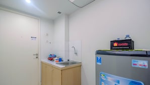 Een kleine kitchenette met een spoelbak, een kast en een koelkast met waterdispenser.