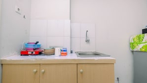 Een keuken met een spoelbak, een aanrecht met verschillende spullen en een kast.