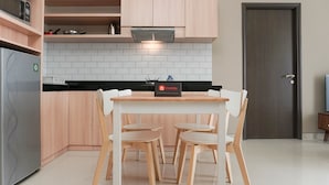 Una cucina moderna con mobili chiari in legno, un piano di lavoro nero e uno schienale rivestito di piastrelle bianche. C'è un tavolo da pranzo con quattro sedie e un cartello che indica un servizio turistico.