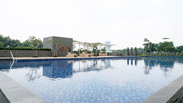 A swimming pool with a tiled edge, lounge chairs, and a small structure with a lifebuoy.