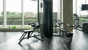 A gym with exercise equipment, large windows, and a view of greenery outside.