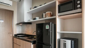 A kitchen with a black refrigerator, a microwave, and a coffee maker on the countertop. - Comfortable Design Studio Apartment Ciputra International (Jakarta)
