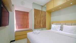 A hotel room with a bed, a bedside table, a mirror, and a window with curtains.