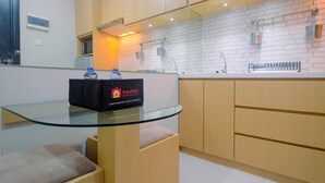 A modern kitchen with wooden cabinets, a glass-top table, and a water dispenser.