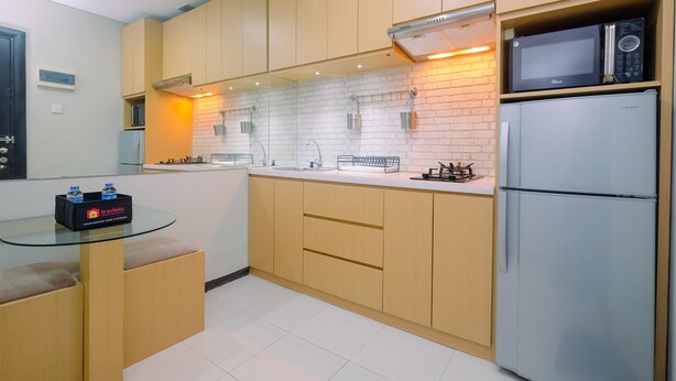 A modern kitchen with wooden cabinets, a glass-top table, a microwave, and a refrigerator.