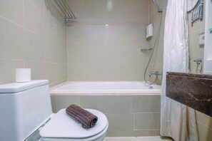 Une salle de bain équipée de toilettes, d’une baignoire et d’un rideau de douche.