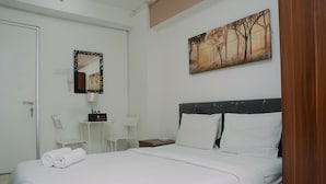 Una habitación de hotel con una cama, un escritorio con silla, un teléfono y un cuadro en la pared.