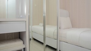A bedroom with a bed, a bench, and a mirror. - Comfortable and Clean 2BR Green Pramuka Apartment (Jakarta)