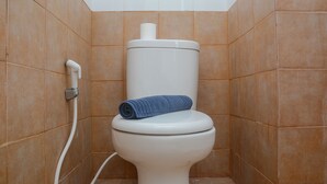 A white toilet with a blue towel on top, set against a wall with brown tiles. - Comfortable and Clean 2BR Green Pramuka Apartment (Jakarta)