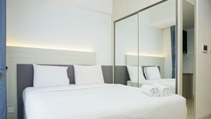 Una habitación de hotel con una cama grande, una mesita de noche, un espejo y un armario.