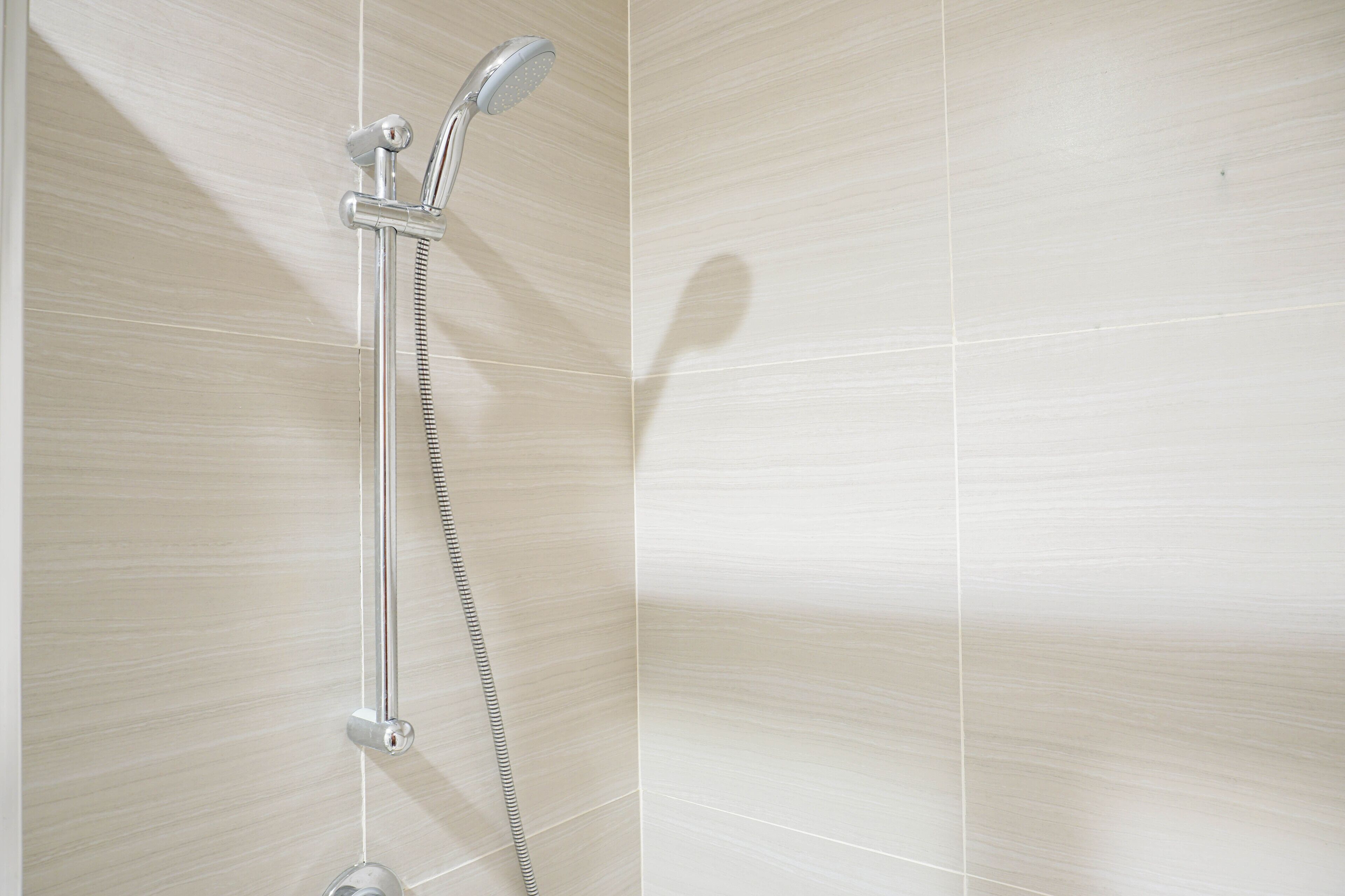 Une douche équipée d’un pommeau de douche à main et d’un robinet mural fixe.