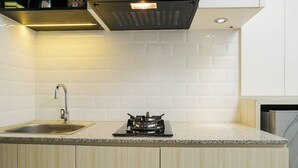 Una cocina moderna con azulejos blancos tipo metro, un lavamanos de acero inoxidable y una estufa a gas.