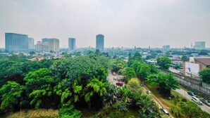 A cityscape with high-rise buildings, dense greenery, and a road with parked cars. - Comfy and New Furnished @ 2BR Kebagusan City Apartment (Jakarta)
