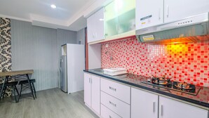 A modern kitchen with white cabinets, a black countertop, and a red-tiled backsplash. - Comfy and New Furnished @ 2BR Kebagusan City Apartment (Jakarta)