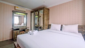 A hotel room with a large bed, a wardrobe, a mirror, and an air conditioning unit. - Comfy and New Furnished @ 2BR Kebagusan City Apartment (Jakarta)