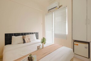 Quarto com cama, mesa de cabeceira com planta, guarda-roupa e unidade de ar condicionado.